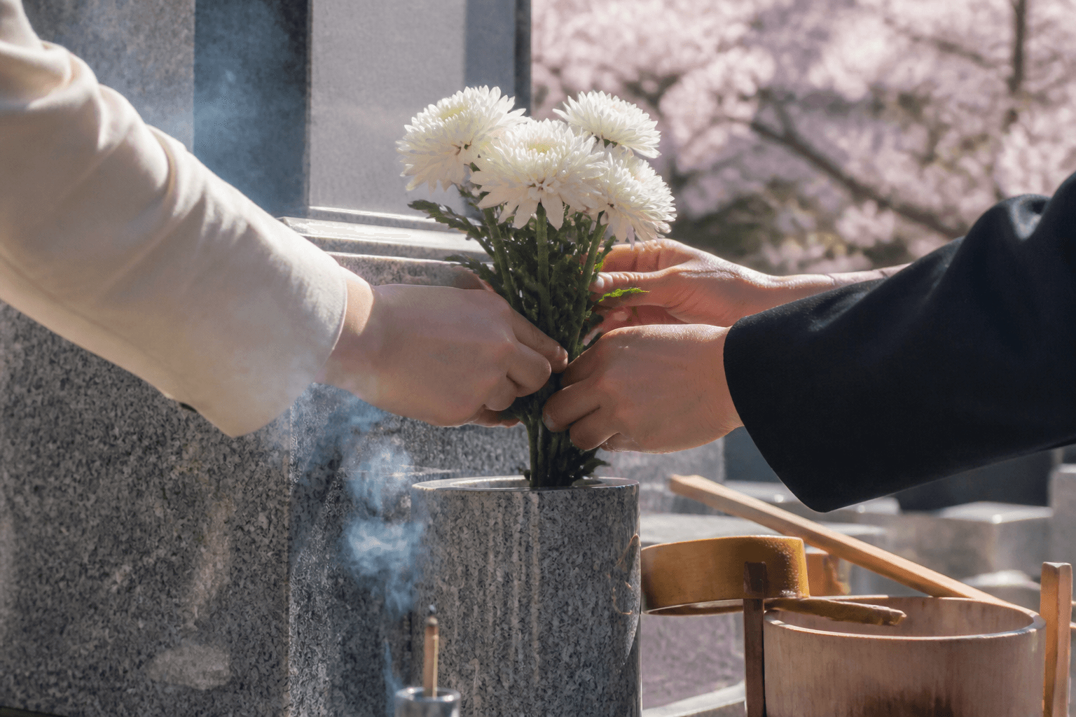 お墓に白い花を供える手元
